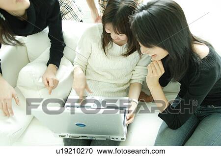 Stock Image - Four young woman looking at computer. Fotosearch
