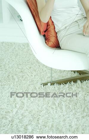 Stock Photograph - Midsection of a young woman sitting in chair. Fotosearch