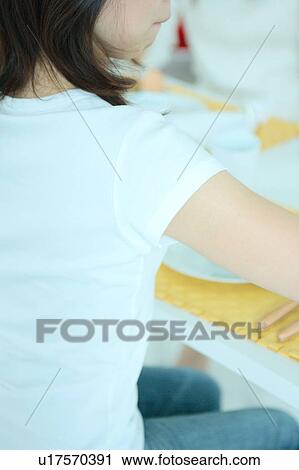 Rear view of a young woman at table View Large Photo Image Stock Image - Rear view of a young woman at table. Fotosearch
