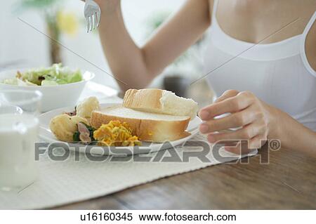Stock Photography - A young woman eating breakfast. Fotosearch