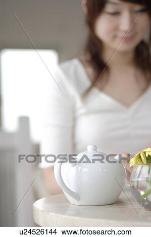 Picture - A young woman sitting at table. Fotosearch