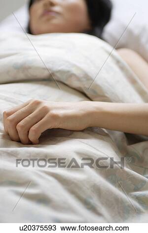 Stock Image - A young woman sleeping in bed. Fotosearch