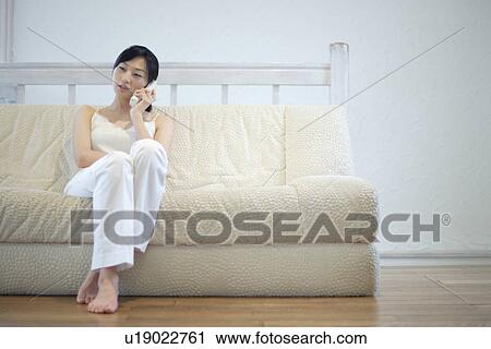 A young woman talking over phone sitting in sofa View Large Photo Image Stock Image - A young woman talking over phone sitting in sofa. Fotosearch