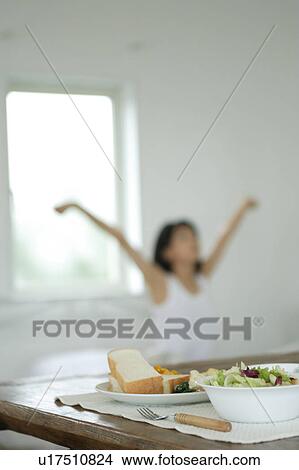 Breakfast at table with a young woman stretching in bed View Large Photo Image Picture - Breakfast at table with a young woman stretching in bed. Fotosearch