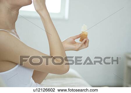 Stock Image - Close-up of a young woman eating bread. Fotosearch
