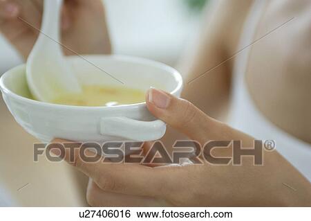 Stock Photograph - Close-up of a young woman eating soup. Fotosearch