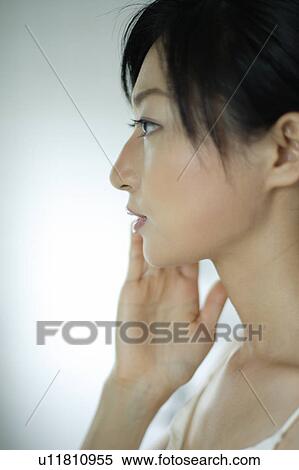 Close-up of a young woman touching her face View Large Photo Image Stock Photography - Close-up of a young woman touching her face. Fotosearch
