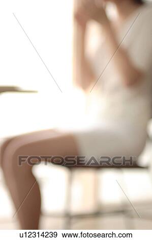 Midsection of a young woman sitting in chair, defocused View Large Photo Image Stock Photo - Midsection of a young woman sitting in chair, defocused. Fotosearch