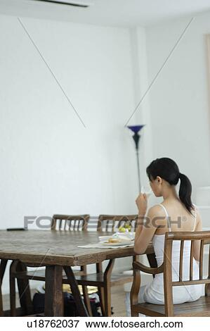 Rear view of a young woman eating breakfast View Large Photo Image Stock Photo - Rear view of a young woman eating breakfast. Fotosearch