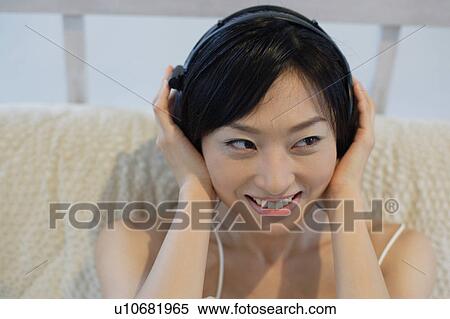 Smiling young woman listening to music View Large Photo Image Stock Photography - Smiling young woman listening to music. Fotosearch