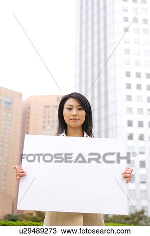 Stock Image - A young business woman holding blank message. Fotosearch