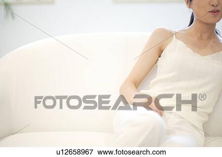 A young woman sitting in sofa View Large Photo Image Stock Photo - A young woman sitting in sofa. Fotosearch