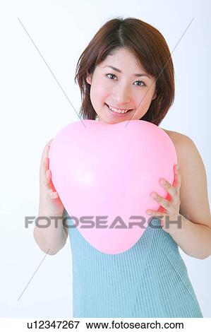 Portrait of a young woman holding balloon View Large Photo Image Stock Photo - Portrait of a young woman holding balloon. Fotosearch
