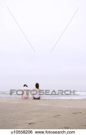 Two young women sitting at beach View Large Photo Image Stock Photograph - Two young women sitting at beach. Fotosearch