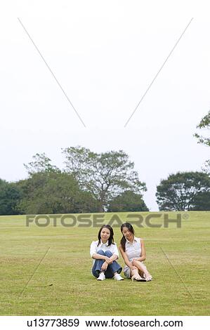 Stock Photo - Two young women sitting in park. Fotosearch