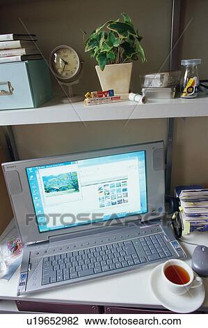 Stock Image - Computer and a cup of tea on desk. Fotosearch