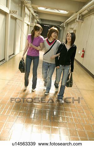 Three college students walking down corridor talking View Large Photo Image Stock Photo - Three college students walking down corridor talking. Fotosearch