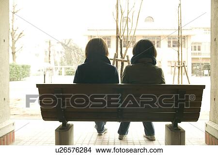 Two college students sitting on bench View Large Photo Image Picture - Two college students sitting on bench. Fotosearch