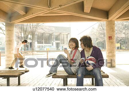Two college students sitting on bench and talking View Large Photo Image Stock Image - Two college students sitting on bench and talking. Fotosearch