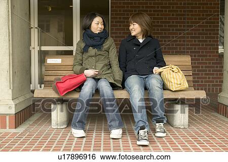 Two college students sitting on bench and talking View Large Photo Image Stock Photograph - Two college students sitting on bench and talking. Fotosearch