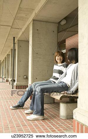 Two college students sitting on bench and talking View Large Photo Image Stock Photography - Two college students sitting on bench and talking. Fotosearch