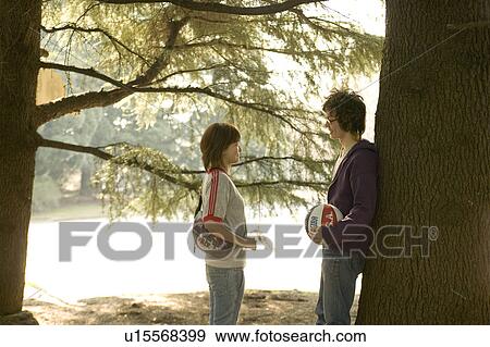 Two college students talking under tree View Large Photo Image Stock Photo - Two college students talking under tree. Fotosearch