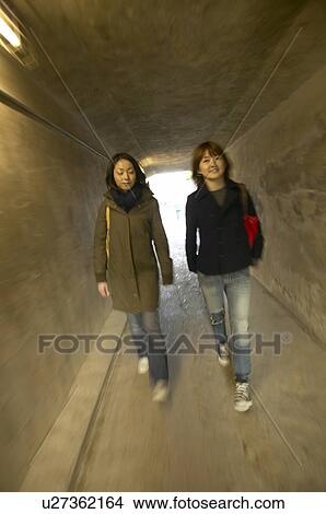 Picture - Two college students walking down corridor, blurred motion. Fotosearch