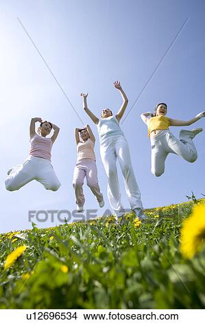 Four young women jumping in field View Large Photo Image Picture - Four young women jumping in field. Fotosearch