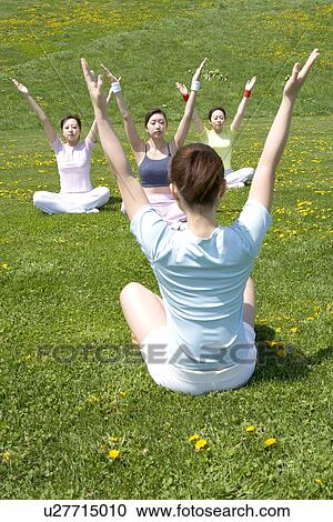 Stock Image - Four young women sitting in field. Fotosearch