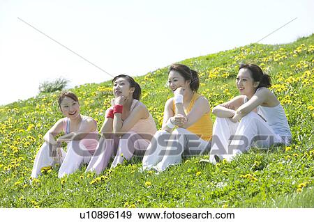 Stock Photo - Four young women sitting in field. Fotosearch