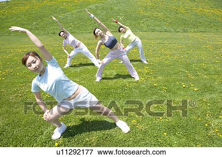 Stock Photo - Four young women stretching in field. Fotosearch