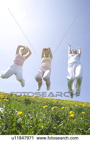 Three young women jumping in field View Large Photo Image Stock Image - Three young women jumping in field. Fotosearch