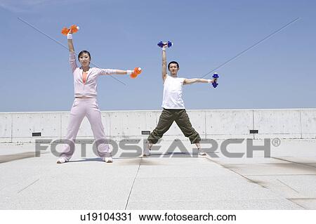Two young adults exercising with dumbbells View Large Photo Image Stock Image - Two young adults exercising with dumbbells. Fotosearch