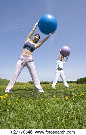 Two young women exercising in field with fitness balls View Large Photo Image Stock Photograph - Two young women exercising in field with fitness balls. Fotosearch