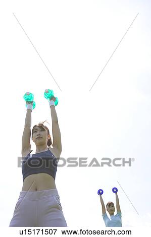 Two young women exercising with dumbbells View Large Photo Image Stock Photo - Two young women exercising with dumbbells. Fotosearch