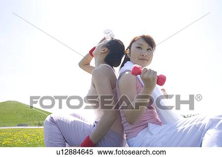 Two young women sitting back to back in field View Large Photo Image Stock Photography - Two young women sitting back to back in field. Fotosearch