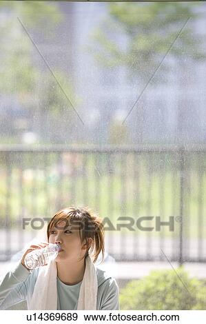 Stock Photo - Young woman drinking water in gym. Fotosearch