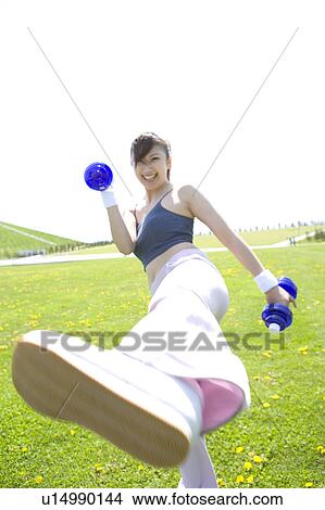 Young woman exercising in field with dumbbells View Large Photo Image Picture - Young woman exercising in field with dumbbells. Fotosearch