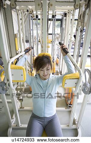 Stock Image - Young woman exercising in gym. Fotosearch