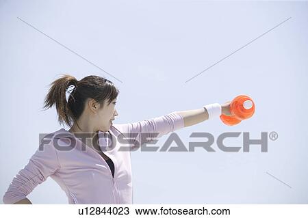 Young woman exercising with dumbbell View Large Photo Image Stock Image - Young woman exercising with dumbbell. Fotosearch