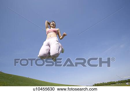 Young woman jumping in field View Large Photo Image Stock Image - Young woman jumping in field. Fotosearch