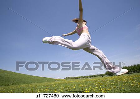 Young woman leaping in field View Large Photo Image Stock Image - Young woman leaping in field. Fotosearch