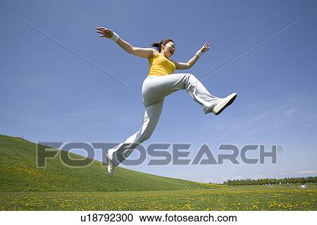 Young woman leaping in field View Large Photo Image Stock Image - Young woman leaping in field. Fotosearch
