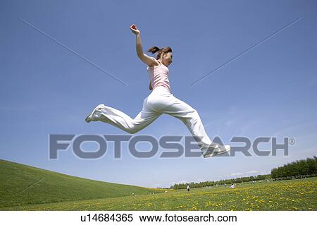 Young woman leaping in field View Large Photo Image Stock Photography - Young woman leaping in field. Fotosearch