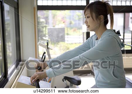 Young woman riding exercise bike in gym View Large Photo Image Stock Image - Young woman riding exercise bike in gym. Fotosearch