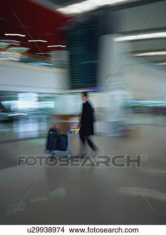 Man walking with luggage at airport, blurred motion View Large Photo Image Picture - Man walking with luggage at airport, blurred motion. Fotosearch