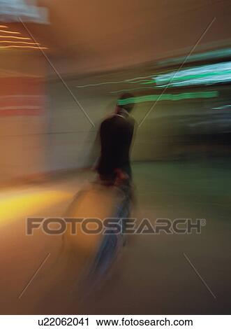 Stock Image - Man walking with luggage at airport, blurred motion. Fotosearch