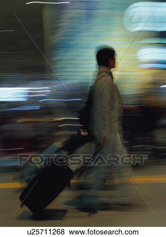 Stock Photo - Man walking with luggage at airport, blurred motion. Fotosearch