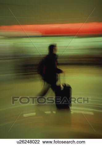 Traveler walking with luggage at airport, blurred motion View Large Photo Image Stock Image - Traveler walking with luggage at airport, blurred motion. Fotosearch