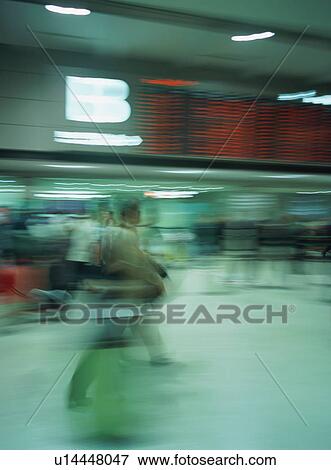 Stock Photo - Traveler walking with luggage at airport, blurred motion. Fotosearch